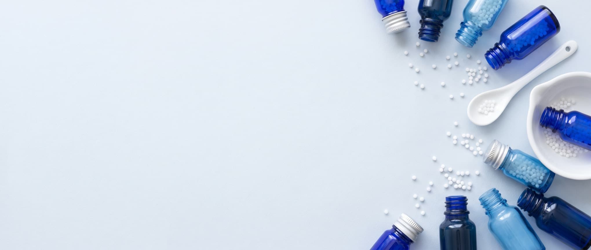 Homöopathische Globuli, blaue Arzneifläschchen, Löffel und Mörser